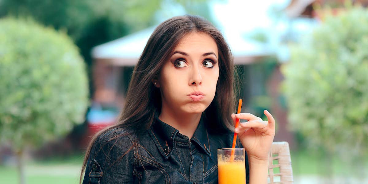 bored and exasperated woman toys with the straw of her drink