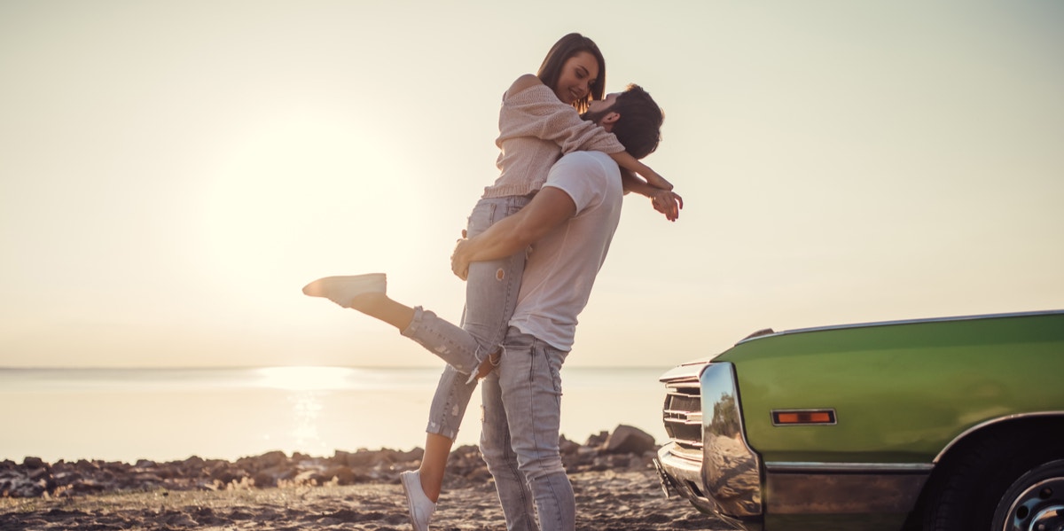 man and woman at beach next to car