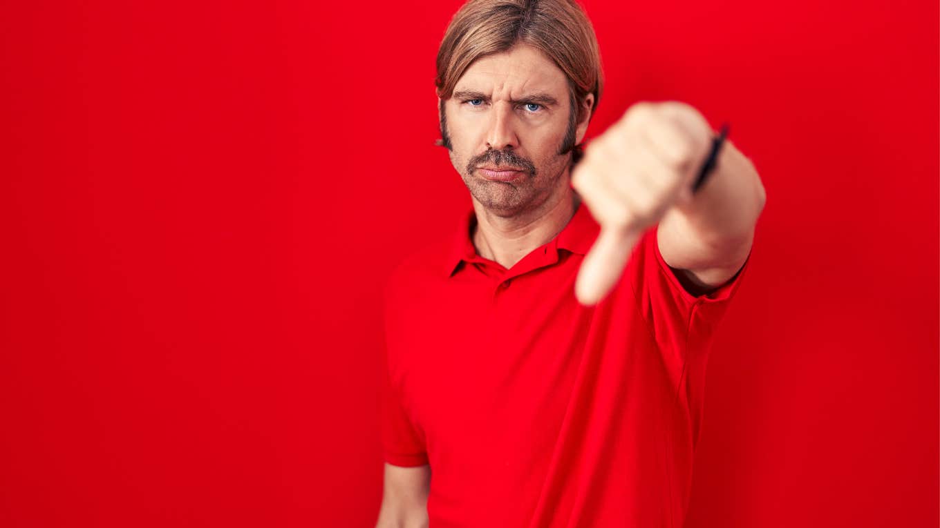 man in his 40s standing in front of red background