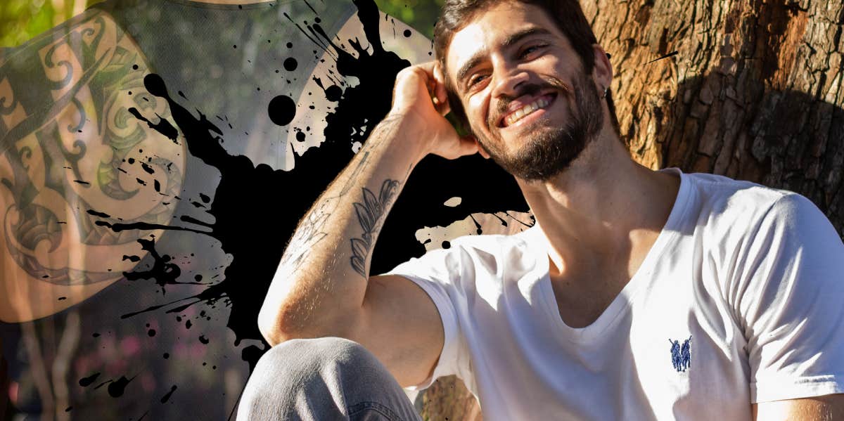 Man with arm tattoo sitting happily outside