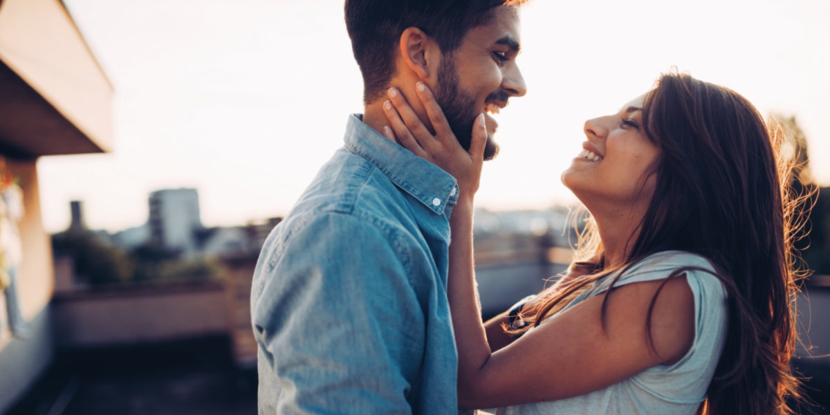 woman holding mans face and smiling