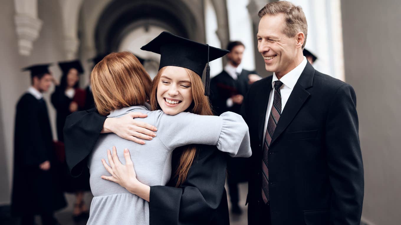 Mom hugging daughter at graduation while dad smiles and looks at them