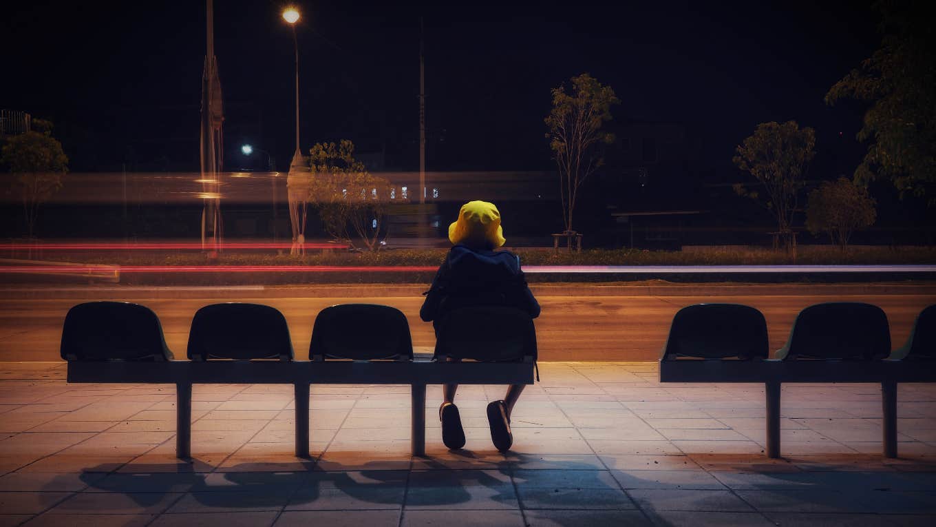 young child sitting at bus stop alone in the dark