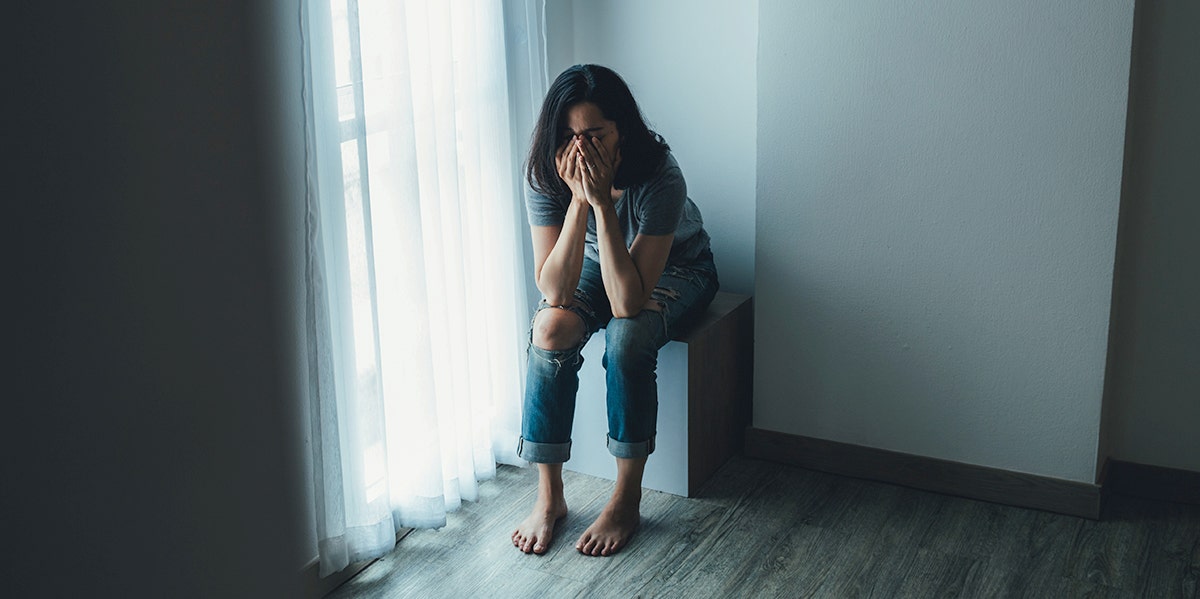 woman sitting in corner with head in hands