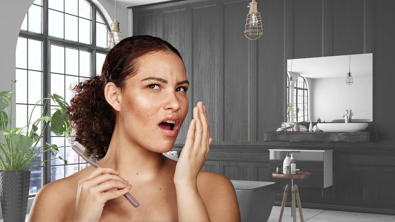 Dentist Shares The Simple Trick To Tell If You Have Bad Breath Woman smelling her bad breath in the bathroom.