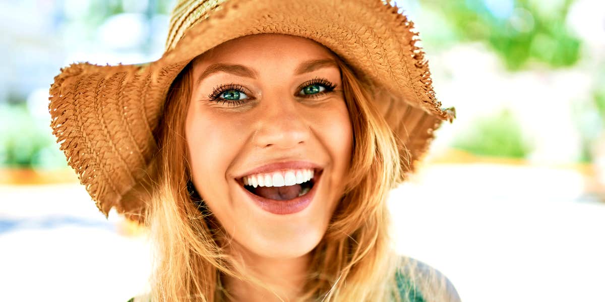 Confident woman in straw hat smiles at camera