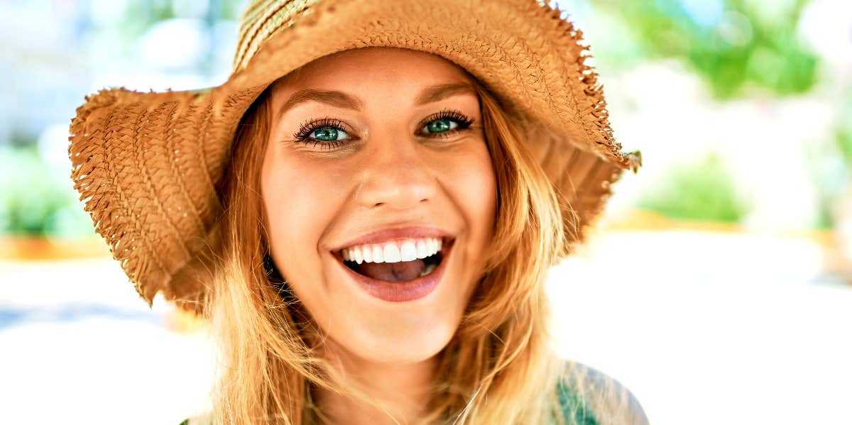 Deserve good things Confident woman in straw hat smiles at camera