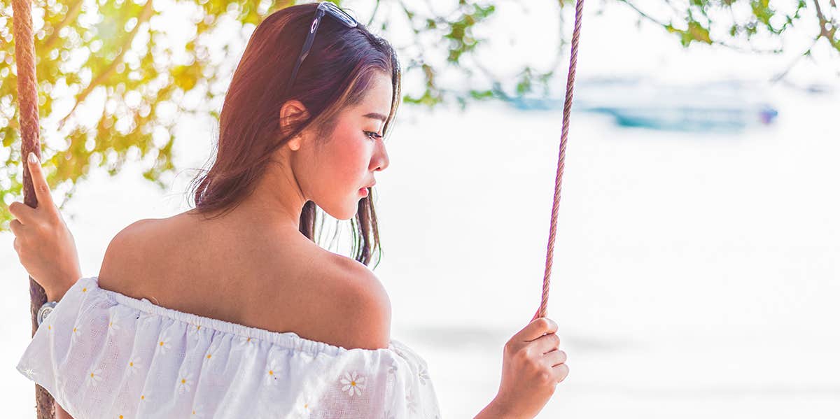 Here’s The Difference Between Being In Love And Just Missing Someone woman sitting on swing