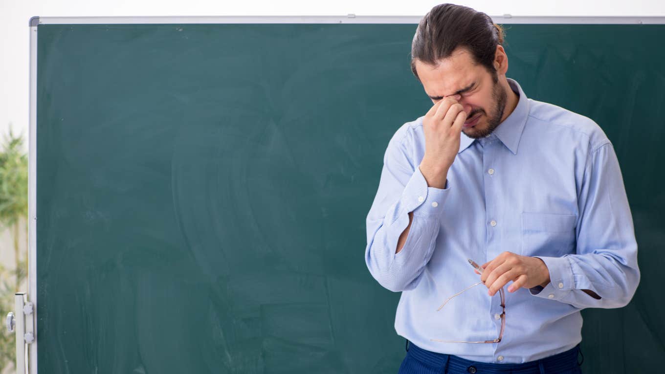 frustrated teacher standing in front of a blackboard