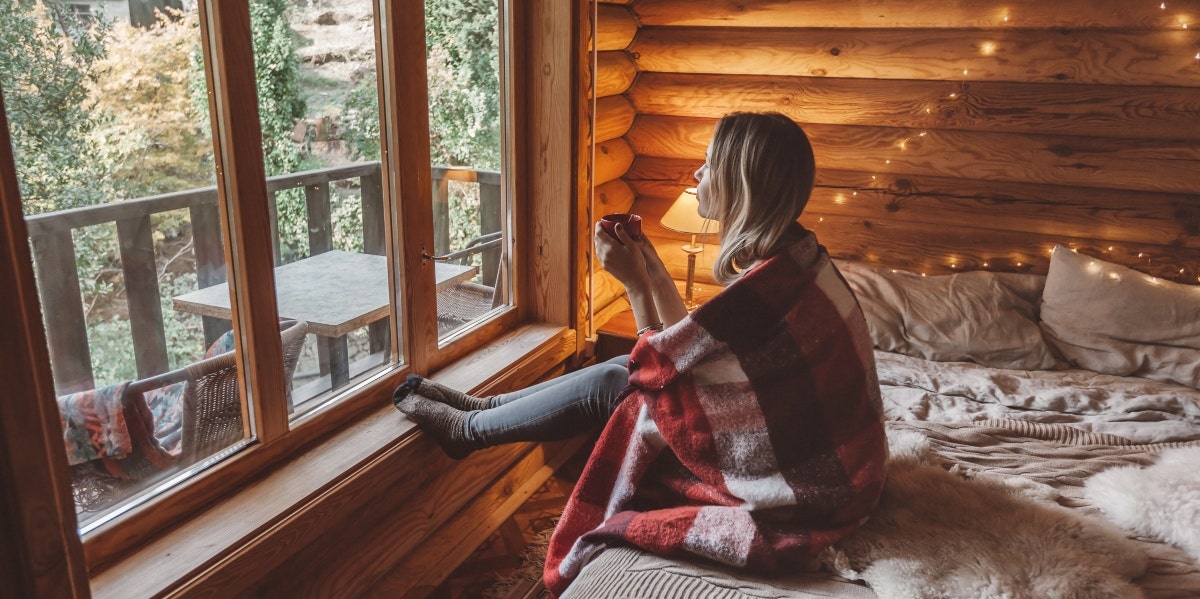 woman wrapped in blanket looking out the window