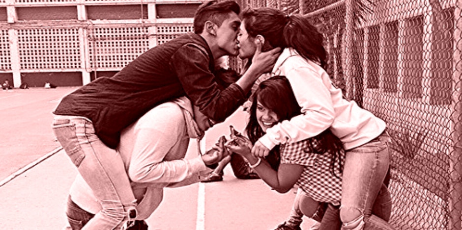 couple kissing with family