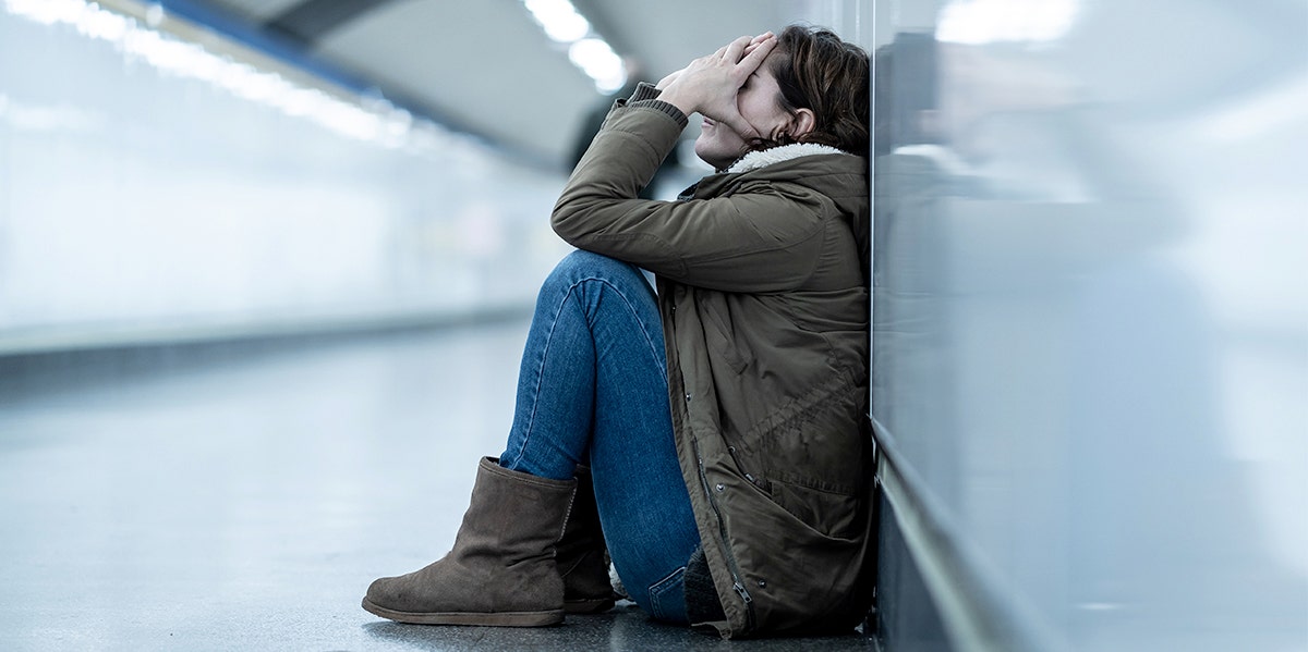 woman with head in hands against wall