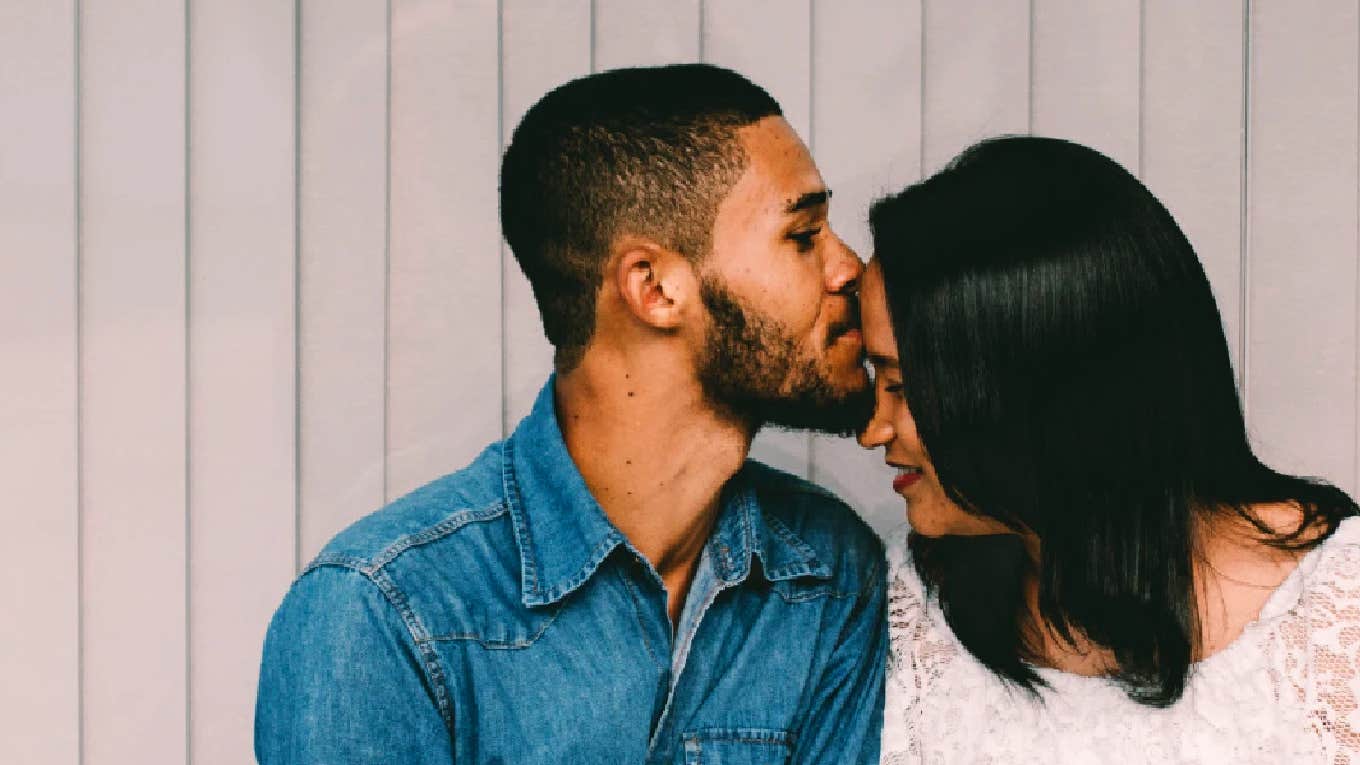 man kissing woman's head