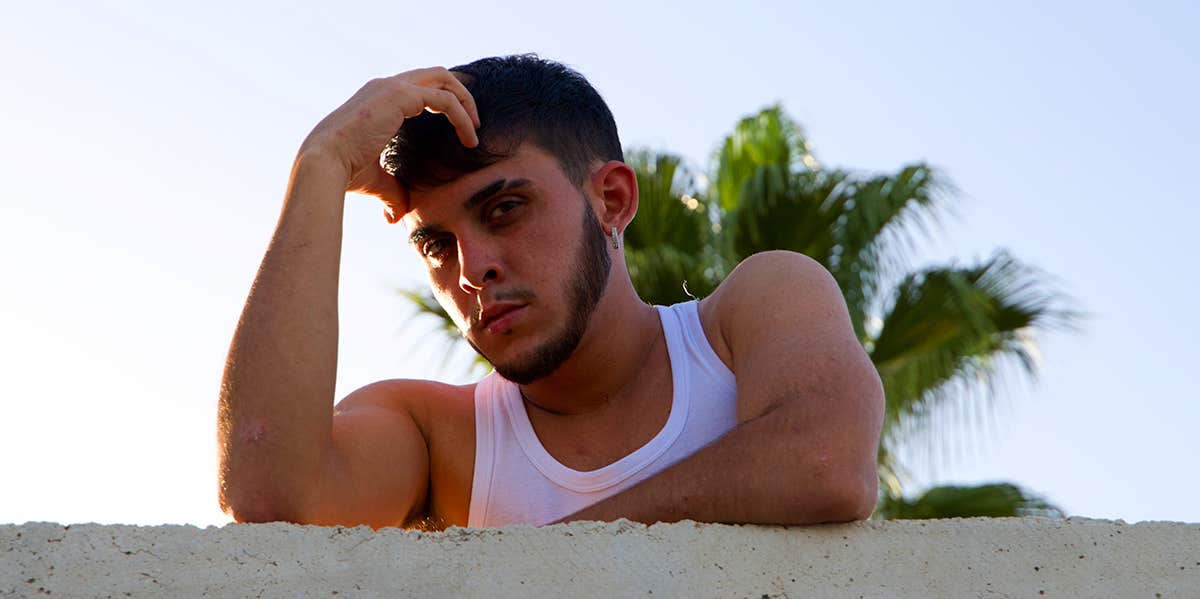 guy in white tank top with hand on head