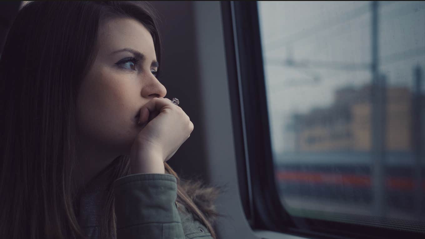 Woman looking out window sad 