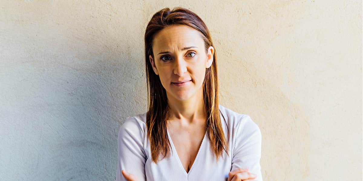 serious-looking caucasian woman looking at camera against a white wall