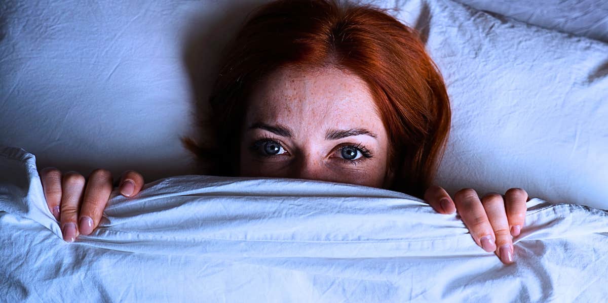 woman lying in bed with eyes open after dreaming about partner cheating
