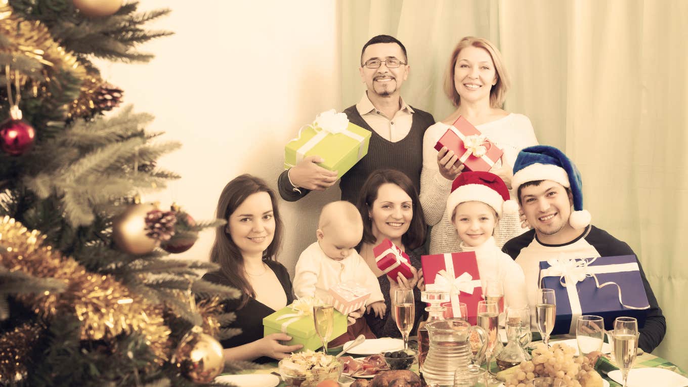 family perfectly posed by Christmas tree with gifts