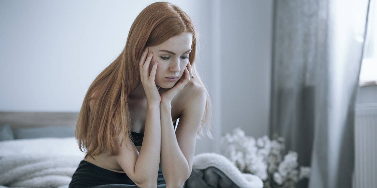 sad woman head in hands sitting on bed