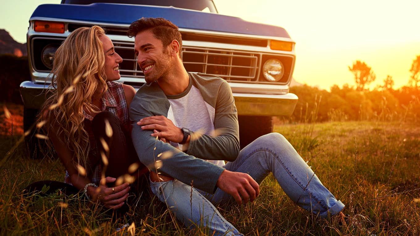 happy couple sitting in front of their car