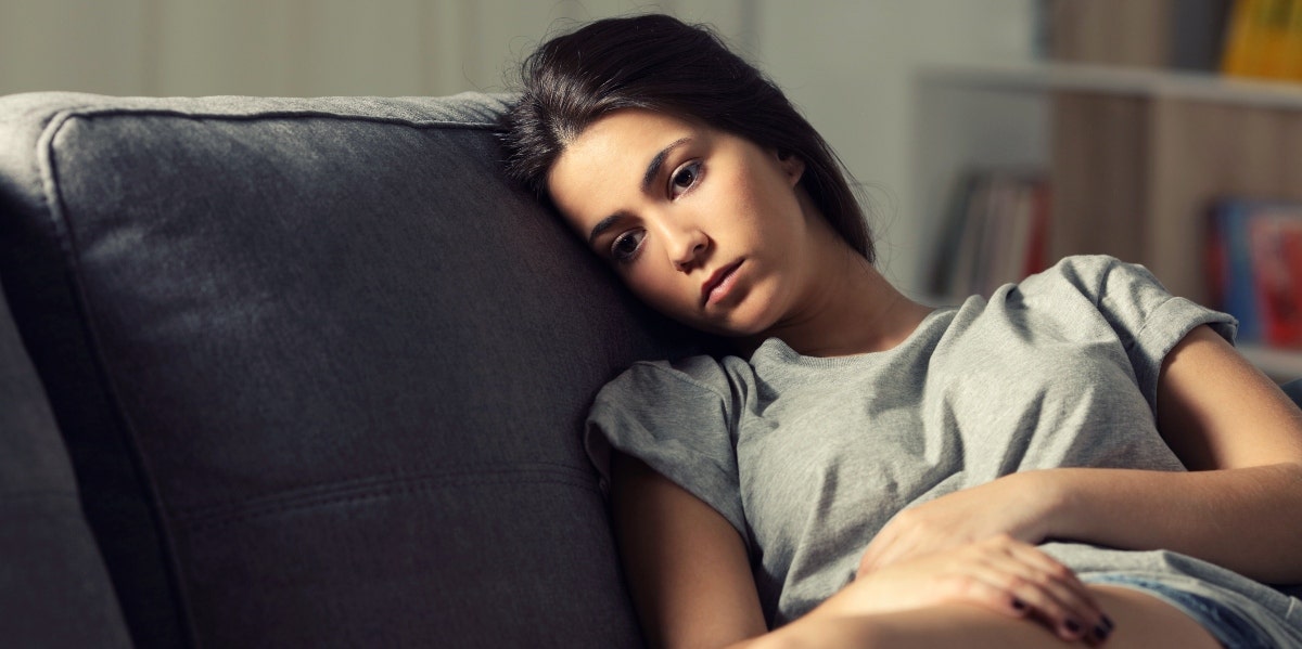 sad woman on couch thinking