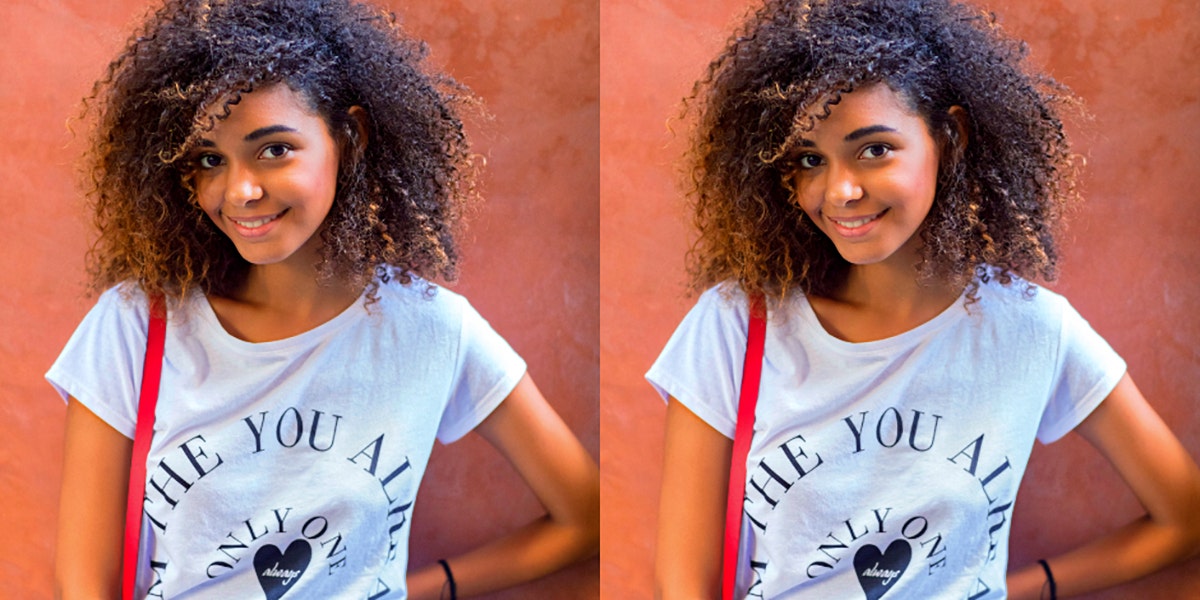 young Black woman smiles at the camera on an orange background