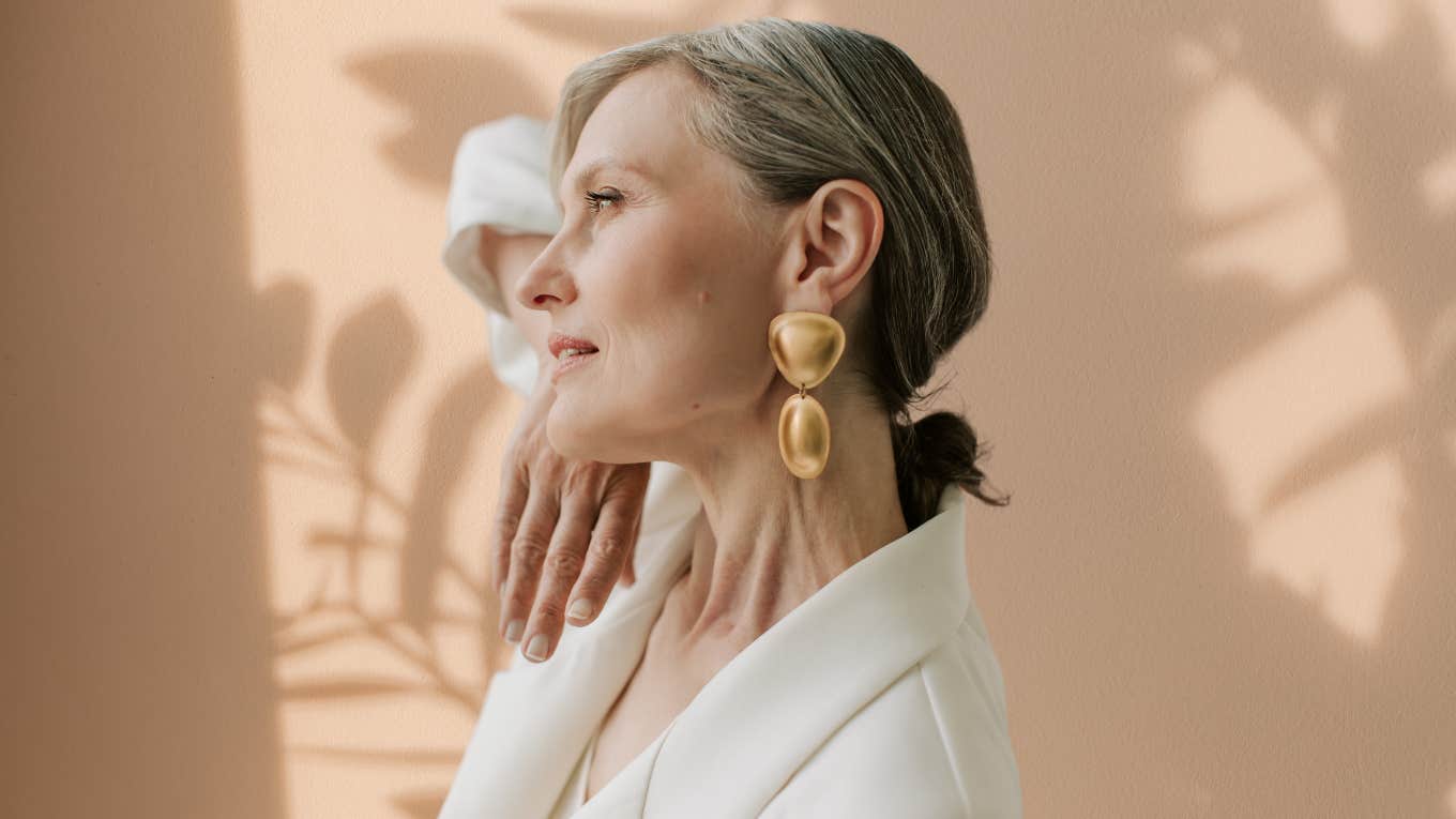 8 Steps Happy People Are Taking To Protect Their Vibe This Year Woman looking happily out a window.