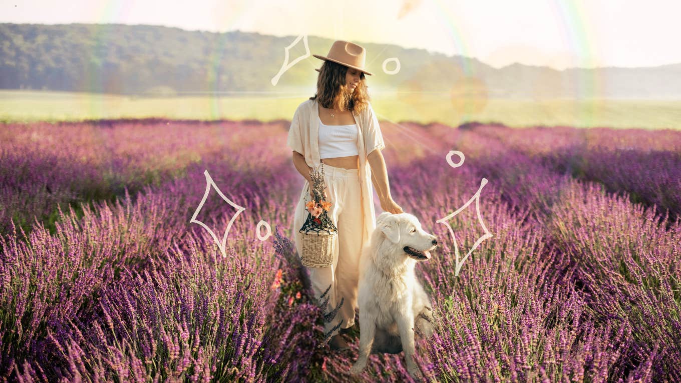 Woman calmly walking in lavender field with her dog 