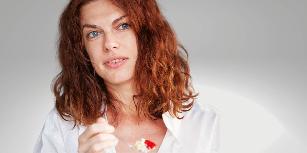 woman in her forties eating a spoonful of dessert