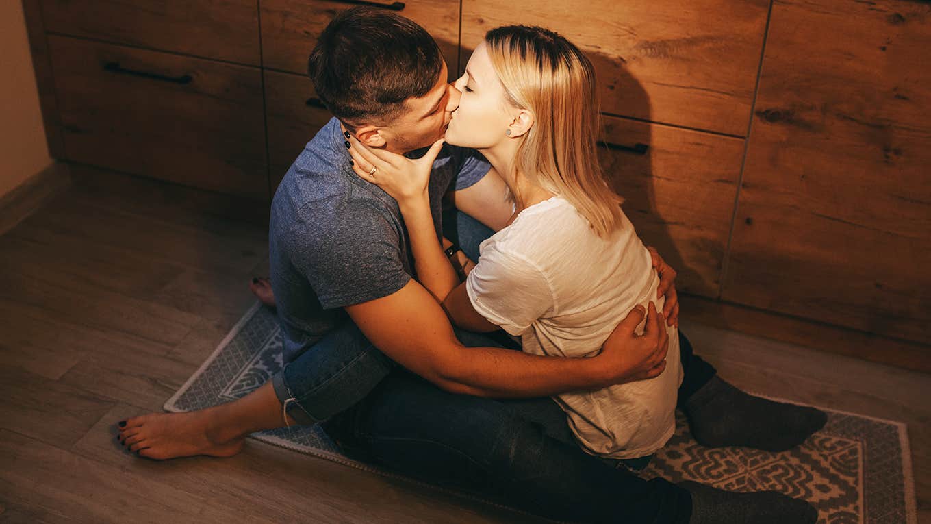 couple sitting on floor in the kitchen and kissing each other