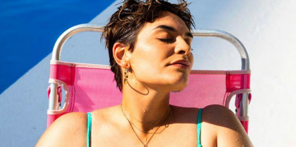 woman with short brown hair sitting in pink sun chair thoughtfully