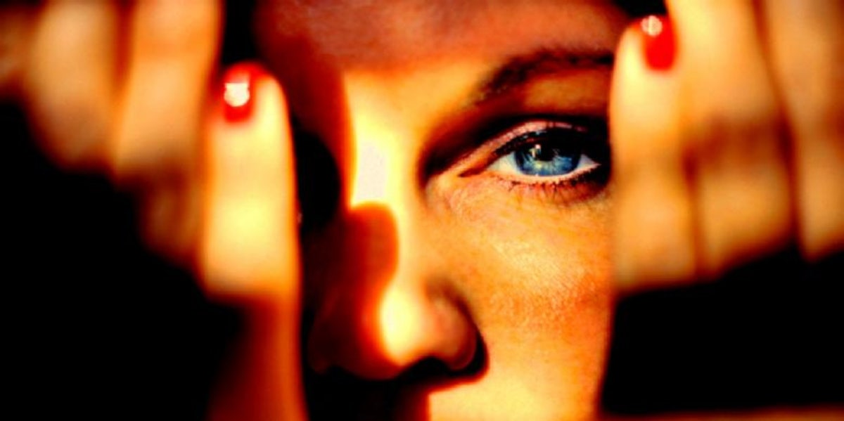 woman with hands in front of face showing her eye