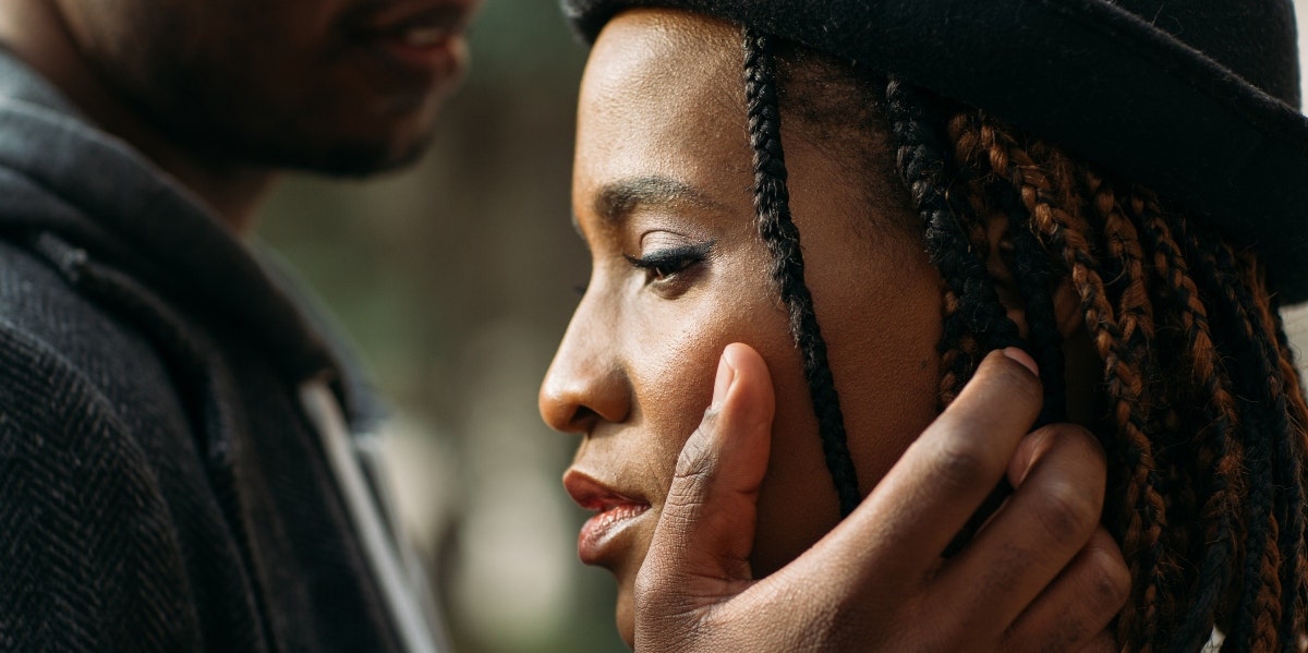 sad woman with man's hand on her face