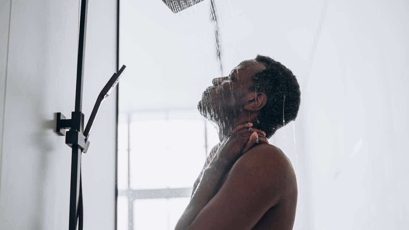 man with eyes closed standing under shower head
