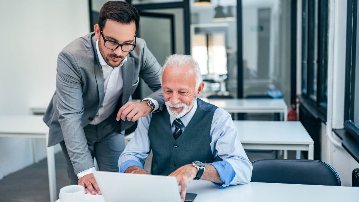 younger employee helping older boss in an office