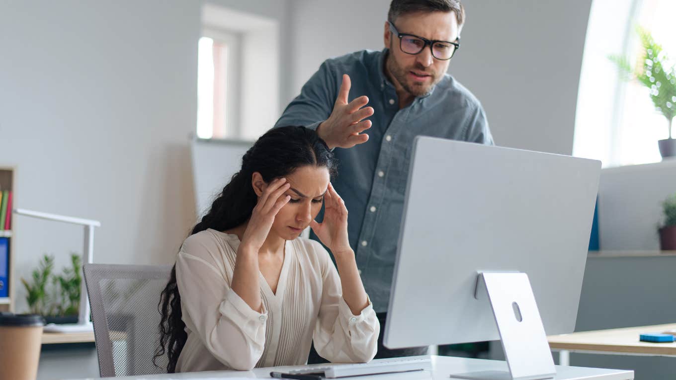 Frustrated male boss scolding young secretary for making mistake in business project at corporate office.