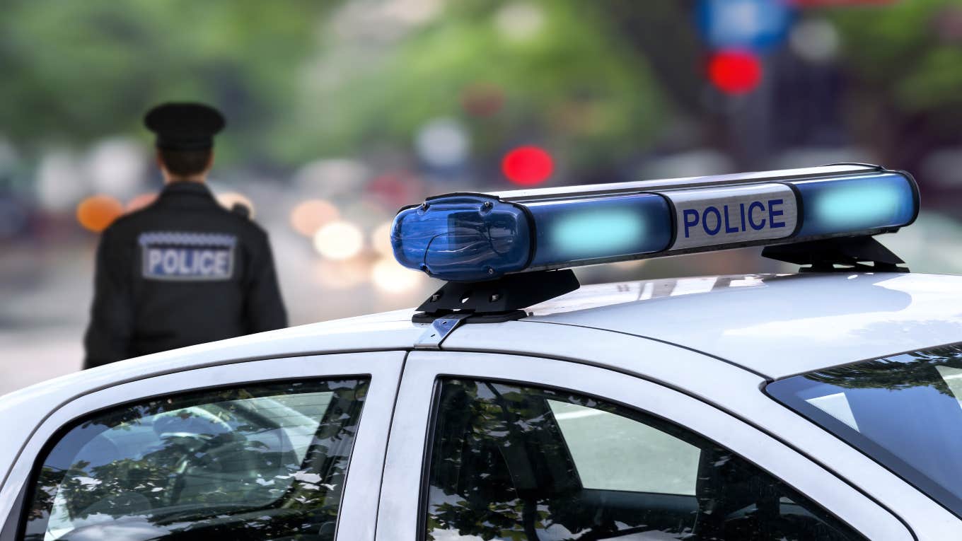 police officer walking away from police car with lights flashing