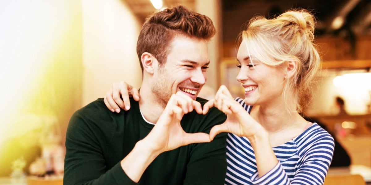 man and woman making a heart together with their hands