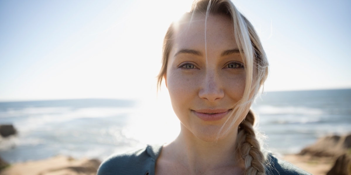 smiling woman with the ocean behind her