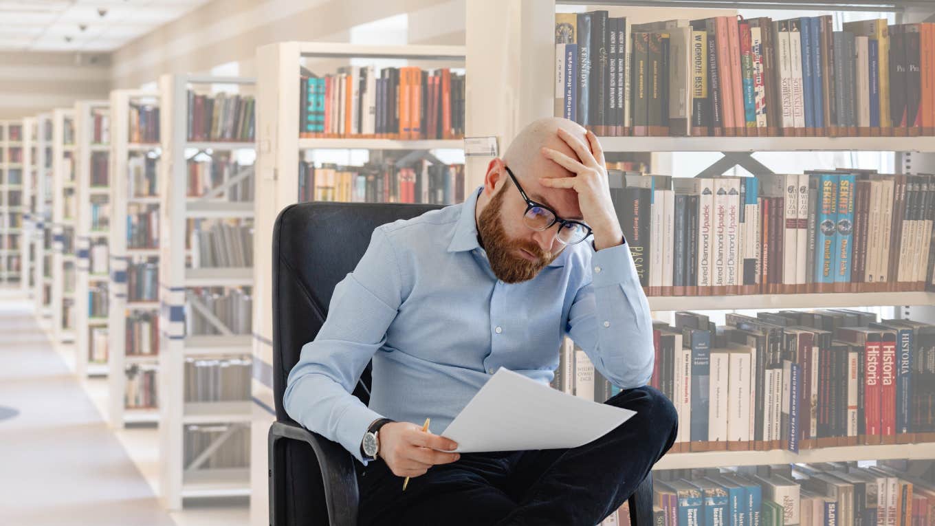 Teacher looks disappointed while sitting in the library. 