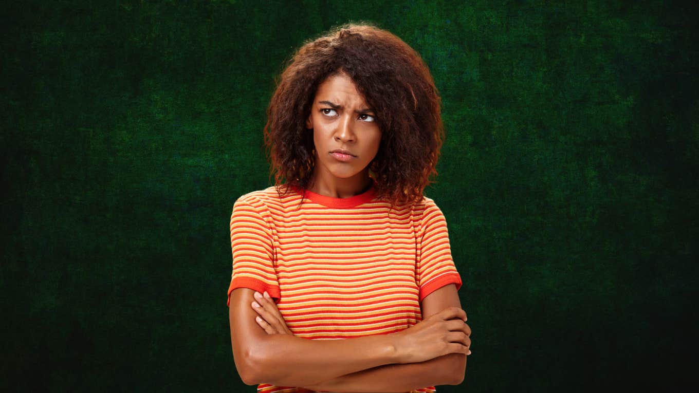 Woman looking frustrated against dark green background