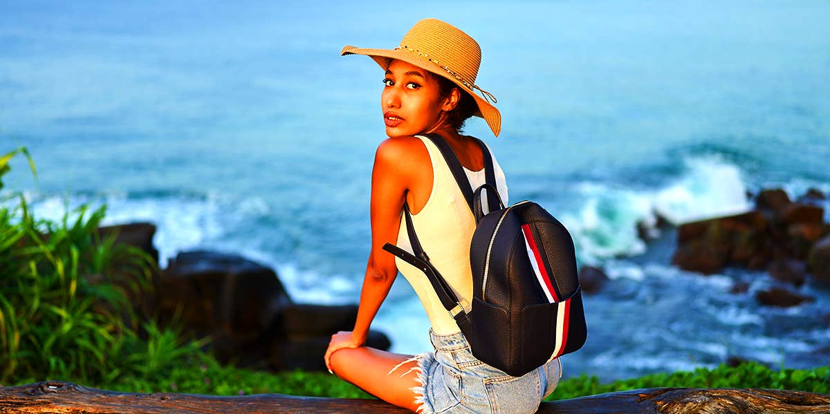 woman sitting on cliff edge overlooking ocean