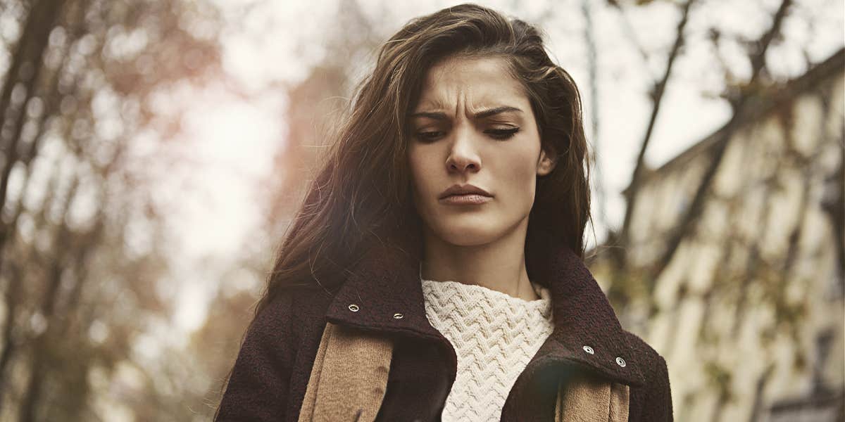 long-haired brunette woman looking upset in the woods, sepia-toned