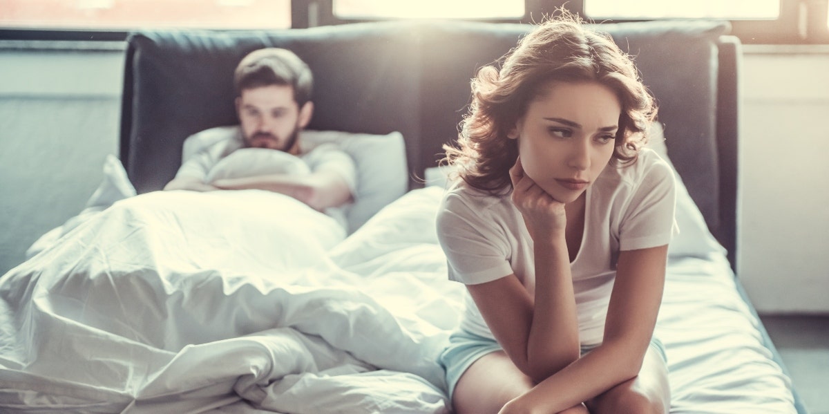 upset woman sitting on bed