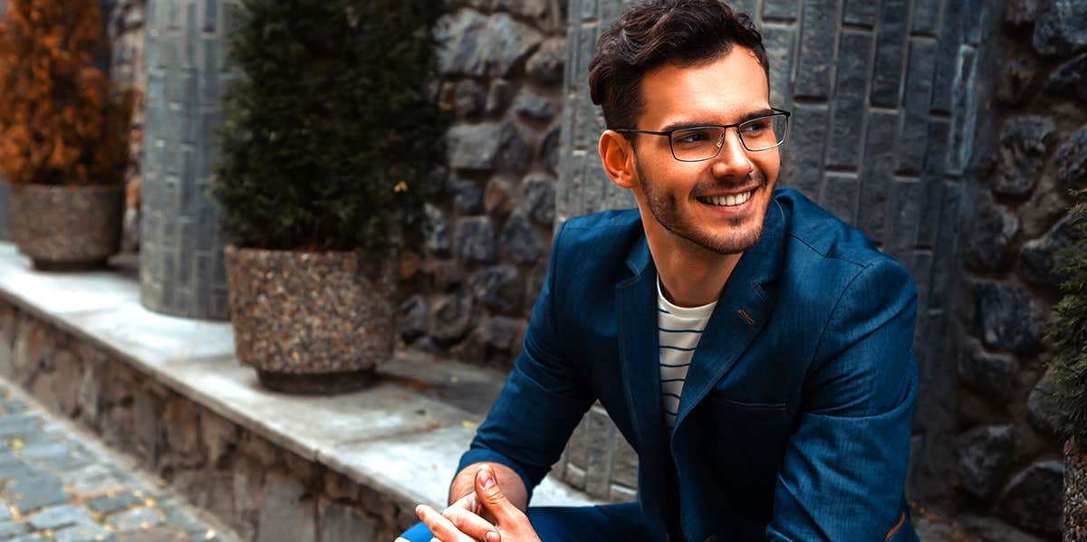 smiling man sitting on curb wearing suit