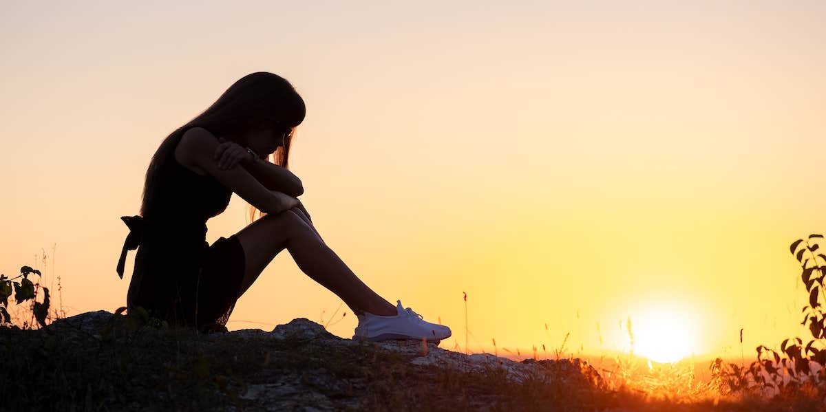 sad girl sitting alone at sunset