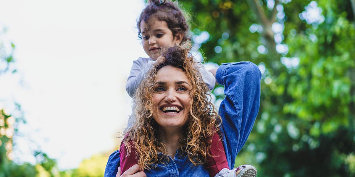 mom carrying daughter on shoulders