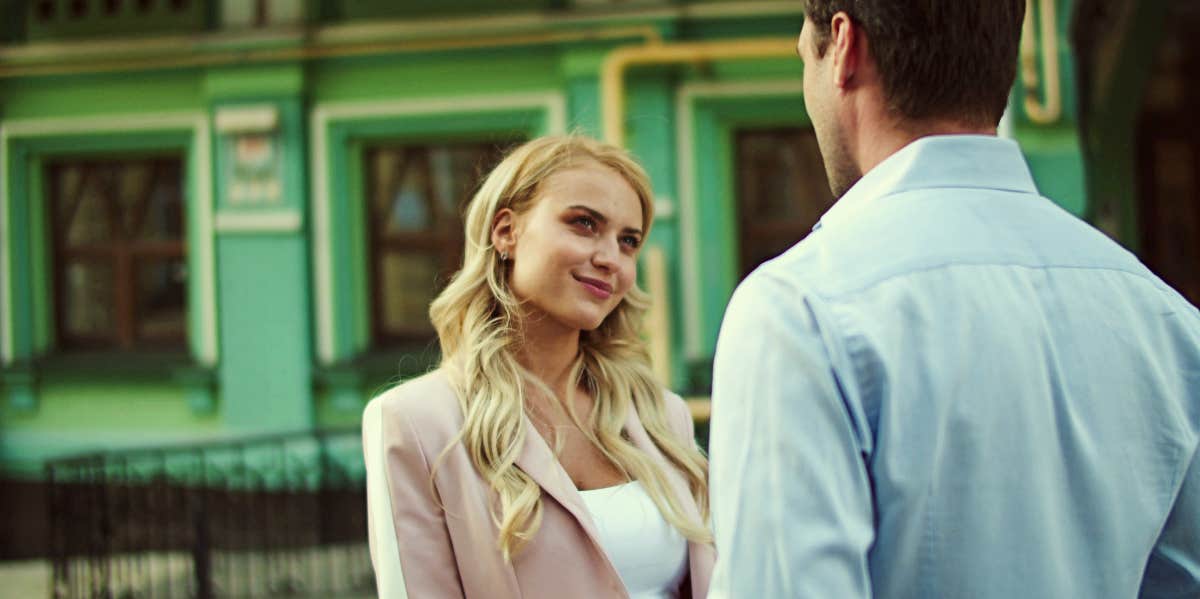 Woman with sardonic smile talks to man