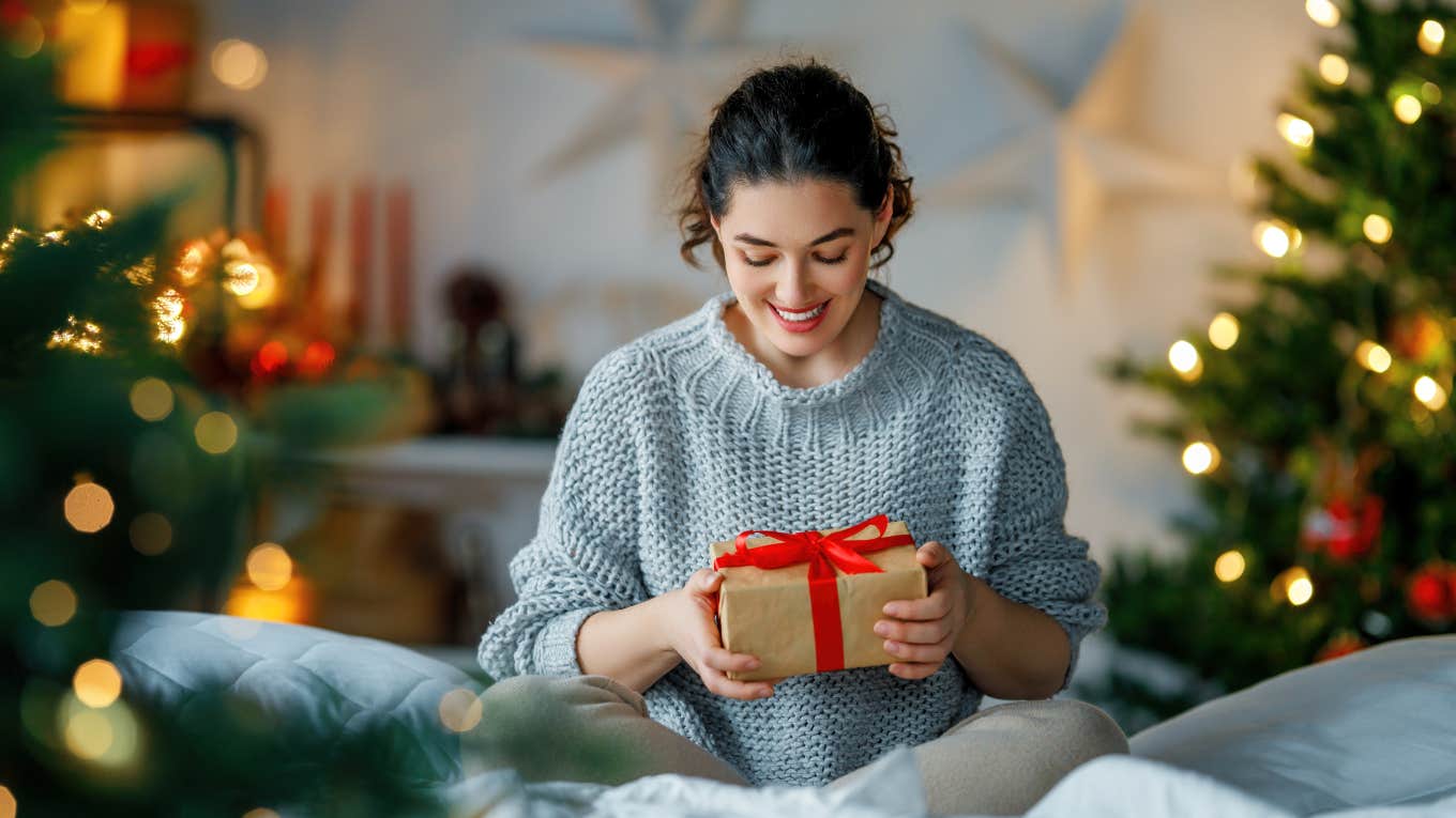 woman holding gift surrounded by Christmas decorations
