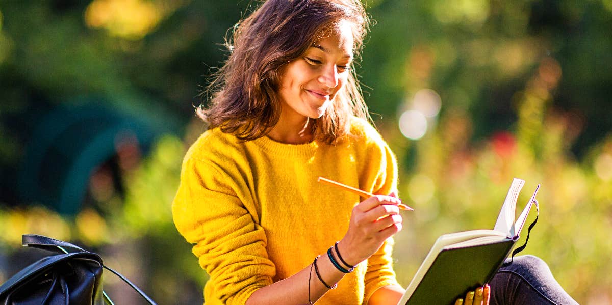 Woman outdoors writes in journal